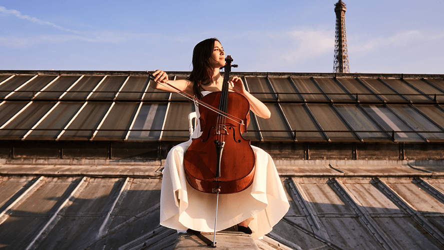 Camille Thomas sitting on a rooftop in Paris with a cello