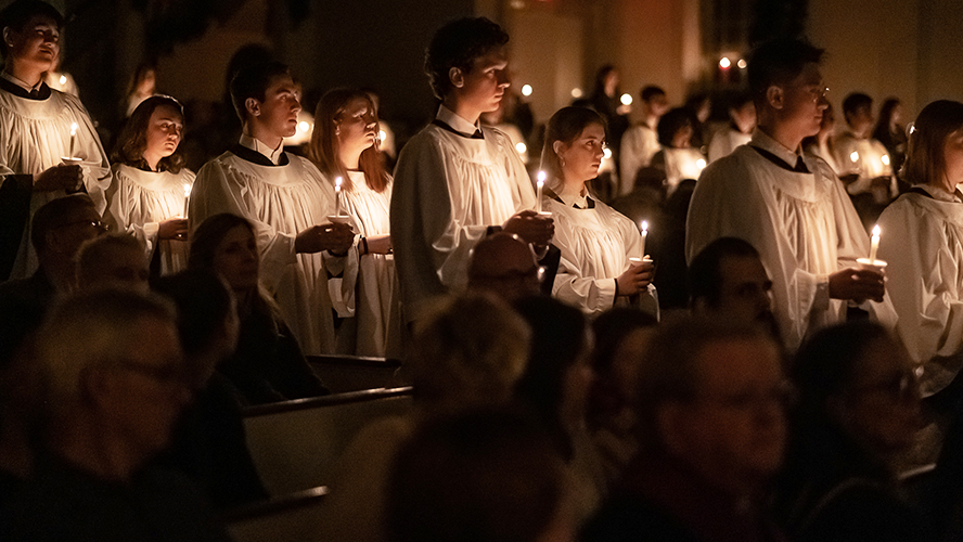 Chorister processional in white robes with candles